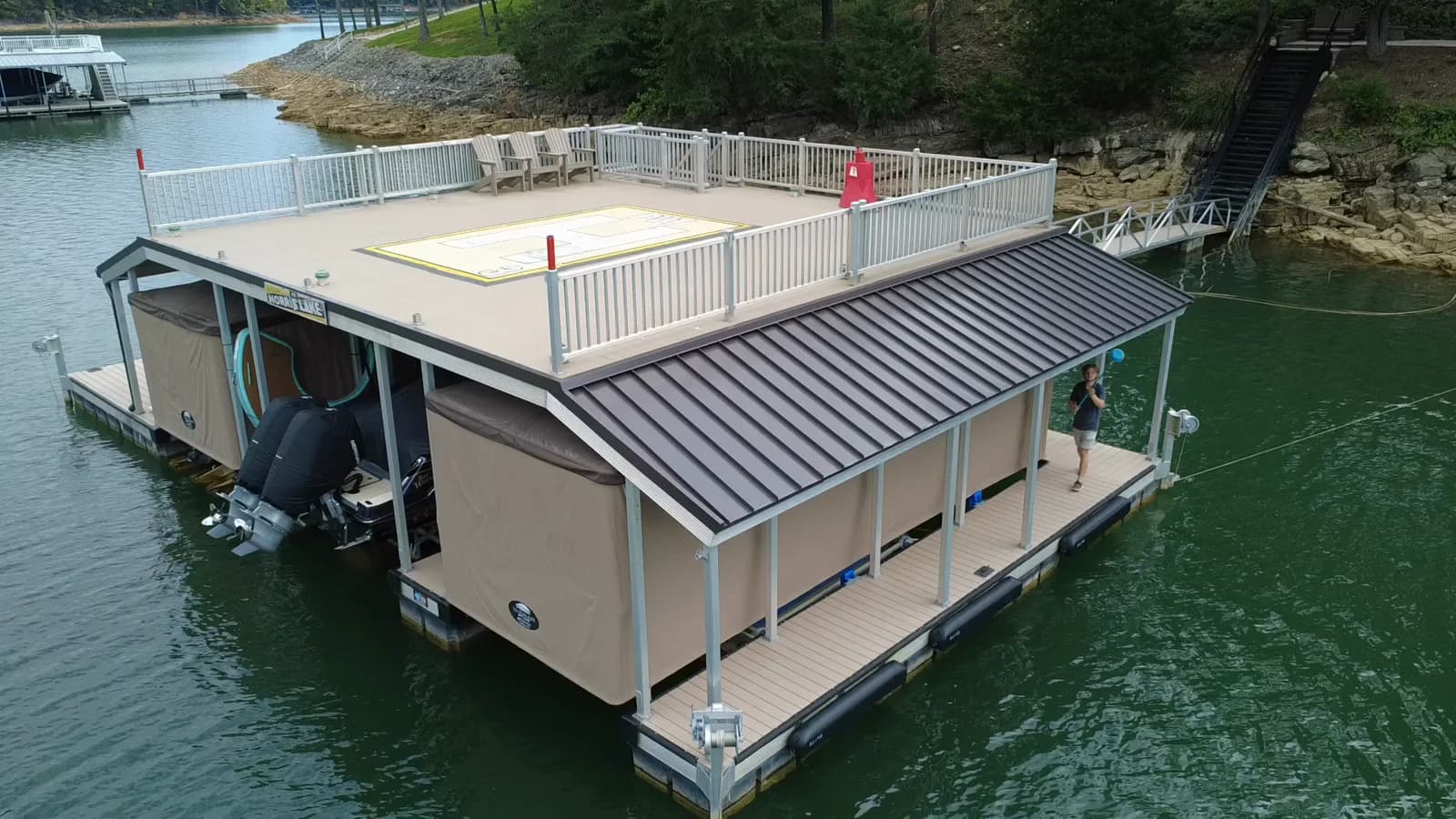 A covered dock and boat slips on Norris Lake, with a team member walking along the waterfront